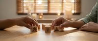Business professional arranging wooden dice with warning symbols on office desk, representing risk management and strategic decision making in corporate environment.