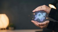 Businessman hands protecting glowing digital shield icon with security symbols representing cybersecurity protection and data safety in modern office.
