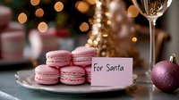 Pink macarons on plate with note for Santa, festive bokeh lights and Christmas ornament in background, cozy holiday setting for seasonal treats.