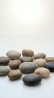 Smooth river stones and pebbles in various neutral tones arranged on white background, isolated for design use on merchandise, packaging, and wellness projects.