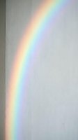 Natural rainbow light spectrum reflection on white wall creating colorful prism effect for interior design and optical phenomena concepts.