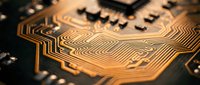 Close-up macro view of golden circuit board traces and electronic components on dark substrate showcasing intricate copper pathways and microchip technology details.