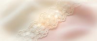 Delicate white lace trim with intricate floral patterns on soft pastel background for wedding, bridal, fashion and romantic design projects.