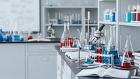Modern laboratory interior with scientific equipment, microscopes, test tubes and colorful chemical solutions on white countertops for research work.