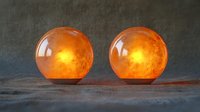 Glowing amber glass spheres with warm illumination against textured dark background, creating atmospheric mood lighting for home decor.