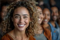 Young mixed race woman with curly hair and bright smile leading diverse group of friends, natural lighting creates warm atmosphere for lifestyle content.