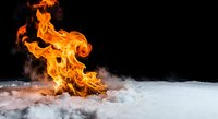 Dramatic orange flames erupting from snowy ground with billowing smoke against black background creating striking fire and ice contrast for creative projects.