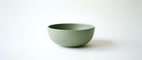 Minimalist sage green ceramic bowl isolated on white background, showcasing clean lines and matte finish for modern kitchen and tableware design.