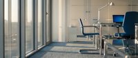 Modern office conference room with blue chairs around glass table near large windows with city view and natural lighting for business meetings.