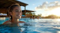 Young woman enjoying sunset swim in infinity pool at luxury resort, radiating joy and relaxation against golden hour sky and water reflections.