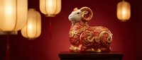 Golden ram figurine with ornate red patterns sits on dark surface against warm red background with glowing paper lanterns for Chinese New Year celebrations.