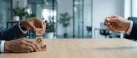 Businessman stacking wooden blocks with smiley face icons, representing customer satisfaction, business growth, and positive feedback in corporate environment.