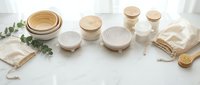 Eco-friendly disposable tableware and sustainable kitchen accessories arranged on white marble surface with natural materials and organic elements.