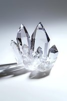 Clear quartz crystal cluster formation with sharp points and natural geometric shapes casting soft shadows on white surface. Spiritual healing concept.