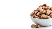 Roasted hazelnuts in white ceramic bowl on white background, nutritious protein-rich snack for healthy eating and cooking ingredient.