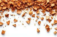 Scattered crushed bronzer or face powder fragments creating border composition on white background, makeup cosmetics texture pattern for beauty industry.