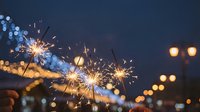Lit sparklers with glowing bokeh lights in evening sky, creating festive celebration atmosphere for holiday events, parties, and New Year festivities.