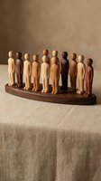 Wooden figurines in various natural tones arranged in a line on a dark wood base, representing diversity and unity for business, community, and organizational concepts.