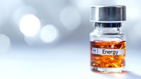 Medical vial with orange liquid labeled "Energy" on blurred light background, representing pharmaceutical or supplement industry.