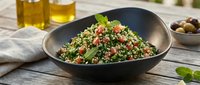 Tabbouleh salad with fresh parsley, tomatoes, and bulgur wheat in black bowl on wooden table with olive oil.