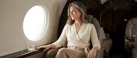 Elegant mature businesswoman relaxing in luxury private jet cabin during flight. Professional female executive enjoying comfortable air travel experience.