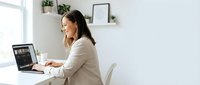 Professional businesswoman working on laptop in modern minimalist home office with plants and natural lighting for remote work productivity.