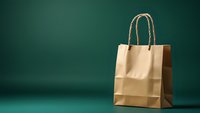 Brown paper shopping bag with handles on dark green background with dramatic lighting and copy space for retail and commerce concepts.