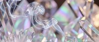 Transparent crystal formations with prismatic light reflections creating rainbow spectrum effects on clear geometric surfaces for luxury design applications.