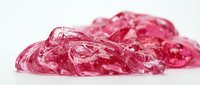 Crushed pink ice or frozen gel substance with crystalline texture and water droplets on white background, suitable for cosmetics, skincare, cooling products, and design projects.