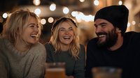 Young diverse friends laughing together at night gathering with bokeh lights background, sharing authentic joyful moment during casual outdoor party.