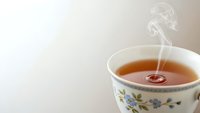 Hot tea cup with floral pattern and steam rising, warm beverage for relaxation and comfort moments.
