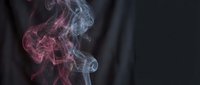Colorful smoke swirls in pink and purple hues against dark background creating abstract atmospheric effect for creative projects and artistic designs.