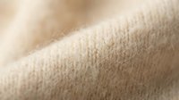Soft beige knitted wool fabric texture with natural fibers, cozy sweater material for fashion design, textile background, warm clothing concept.