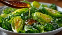 Roasted Brussels sprouts with golden honey glaze drizzling from wooden spoon in white bowl. Fresh green vegetables with caramelized edges for healthy cooking.
