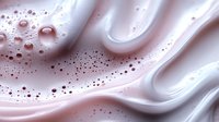 Luxurious pink and white cream swirls with delicate bubbles create soft flowing abstract waves and textures in cosmetic skincare background pattern.