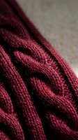 Close-up of burgundy cable knit wool sweater showing detailed texture and stitching patterns for cozy winter fashion and handmade clothing concepts.