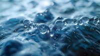 Macro photography of transparent water drops with beautiful bokeh effect on blue background, perfect for environmental or pure water advertising concepts.