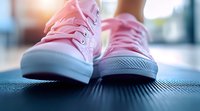 Pink canvas sneakers on dark textured surface with soft focus and morning light creating atmospheric mood for lifestyle and fashion concepts.