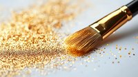 Makeup brush with scattered gold glitter powder on white surface, close-up view showing cosmetic application technique and luxurious shimmer effect.