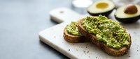 Avocado toast on rustic bread with seeds and spices, served on wooden board. Healthy breakfast or snack concept with fresh ingredients for nutritious eating.