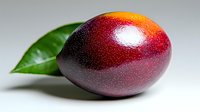Fresh ripe mango with water drops and green leaf on light background, close up view of tropical fruit with vibrant red and yellow gradient colors.