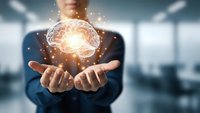 Businessman holding glowing brain hologram with network connections representing artificial intelligence, innovation and digital transformation in modern office.
