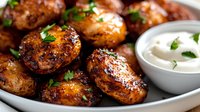 Grilled mushrooms with spicy marinade and creamy dip sauce garnished with fresh herbs on plate, close up view of appetizing vegetarian dish served as starter.