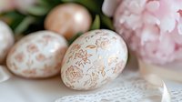 Decorated Easter eggs with floral patterns in soft pastel tones, featuring hand-drawn designs on natural shells, surrounded by fresh pink peonies and greenery for spring holiday celebrations.