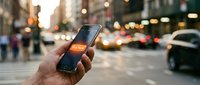 Hand holding smartphone with glowing Buy Now button on busy city street, mobile shopping and e-commerce concept for digital marketing and retail campaigns.