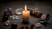 Mystical altar setup with burning candle, crystals, pentagram symbol and ritual tools for spiritual practices, meditation and esoteric ceremonies.