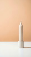 Minimalist beige candle in wooden holder against warm peach background. Modern home decor styling for interior design and lifestyle photography.
