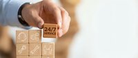 24/7 customer service concept with hand placing wooden block featuring service icon among other support symbols.