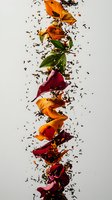 Vibrant rose petals in orange and burgundy cascade vertically with scattered dark tea leaves creating dynamic movement against white background for food and beverage designs.