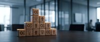 Wooden blocks stacked in pyramid shape with business icons including gears, arrows, and light bulbs on office desk, symbolizing growth strategy.